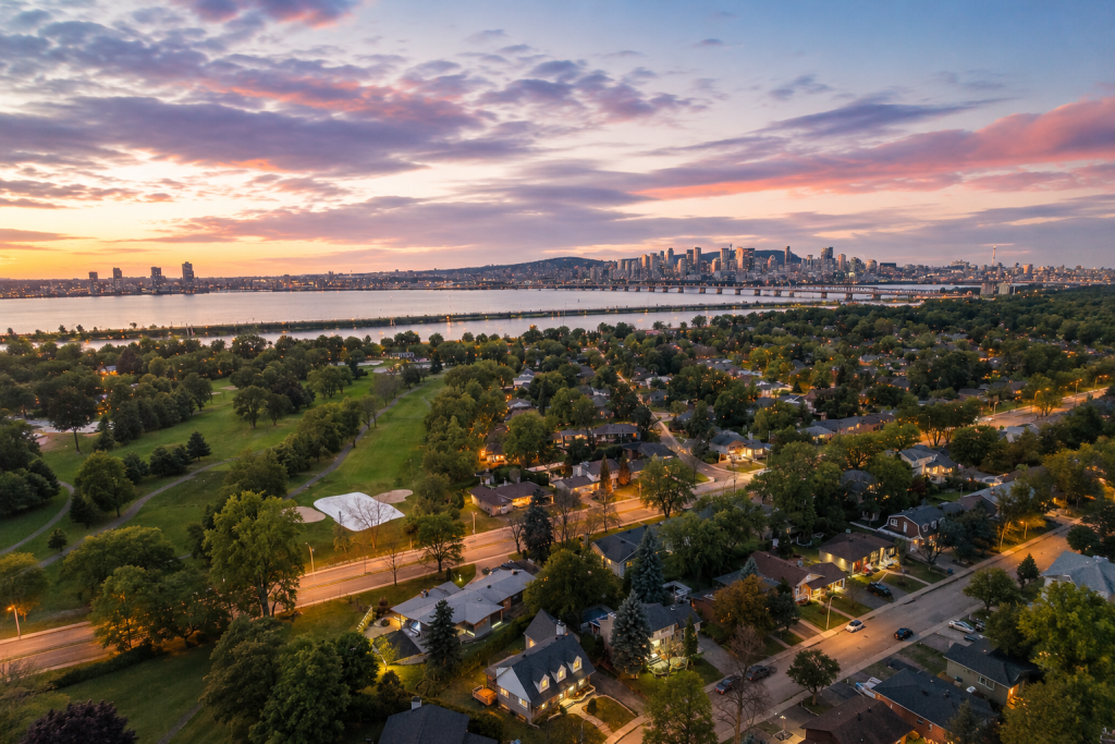 Vue aérienne du quartier résidentiel de Saint-Lambert avec le fleuve Saint-Laurent et le centre-ville de Montréal en arrière-plan.